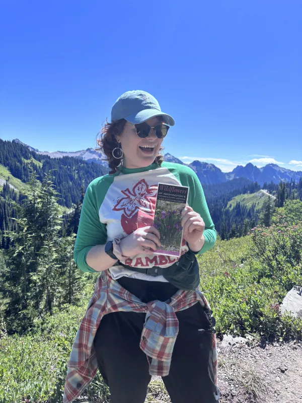 nico happily stands in front of Mt. Ranier with a subalpine wildflowers guide in hand 